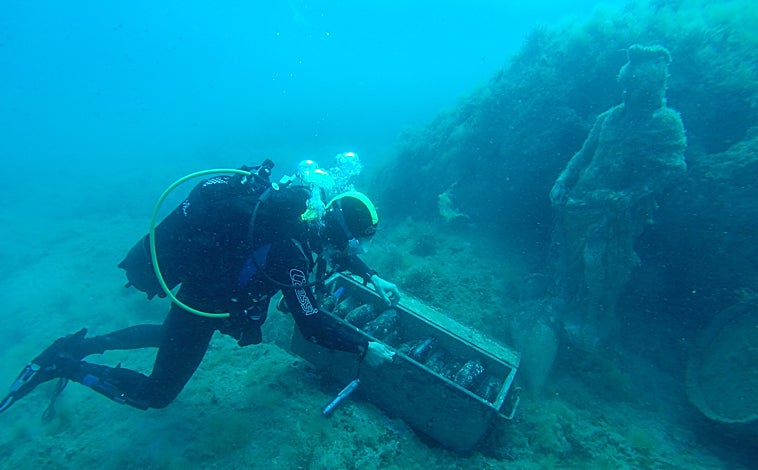 Imagen principal - Foto superior, un buzo destapa un arcón con vinos de la bodega alicantina Vina Maris. Arriba: izquierda, una de las estructuras que atesora los caldos de la marca Crusoe Treasure y, derecha, los depósitos del vino blanco Habla del mar
