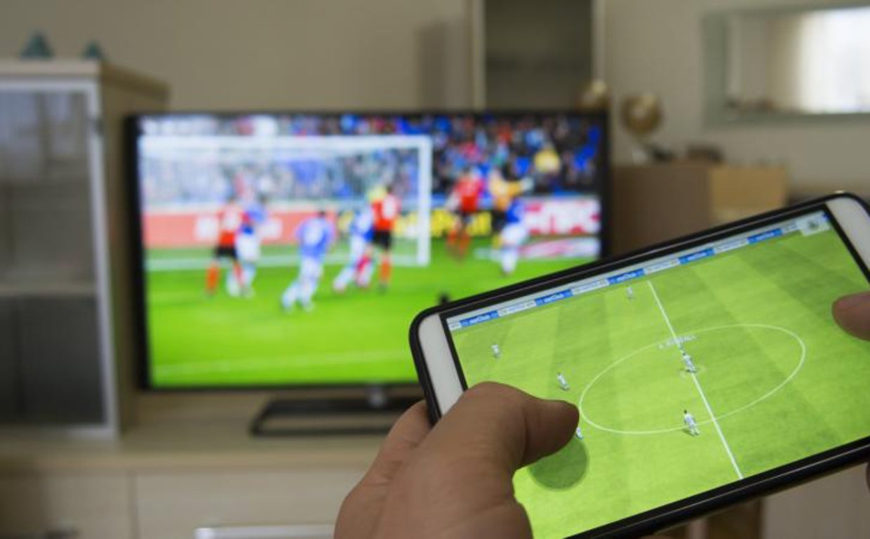 Un usuario sintoniza un partido de fútbol en la televisión mientras ve un vídeo en su teléfono móvil