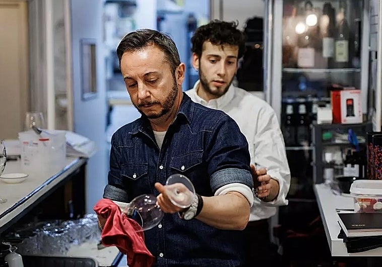 Un camarero limpia una copa de vino en el restaurante 'Estando contigo' en Madrid (España).