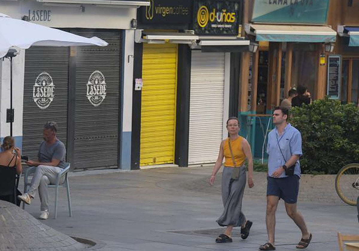 Tiendas cerradas por vacaciones en un barrio de Sevilla