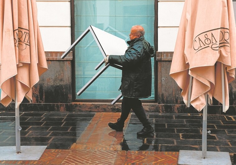 Un empleado recoge la terraza en un establecimiento hostelero en Málaga