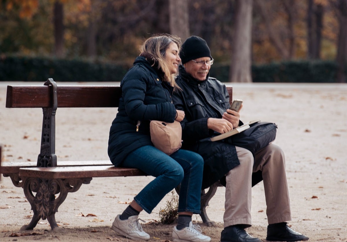 Dos personas sentadas en el banco de un parque de Madrid