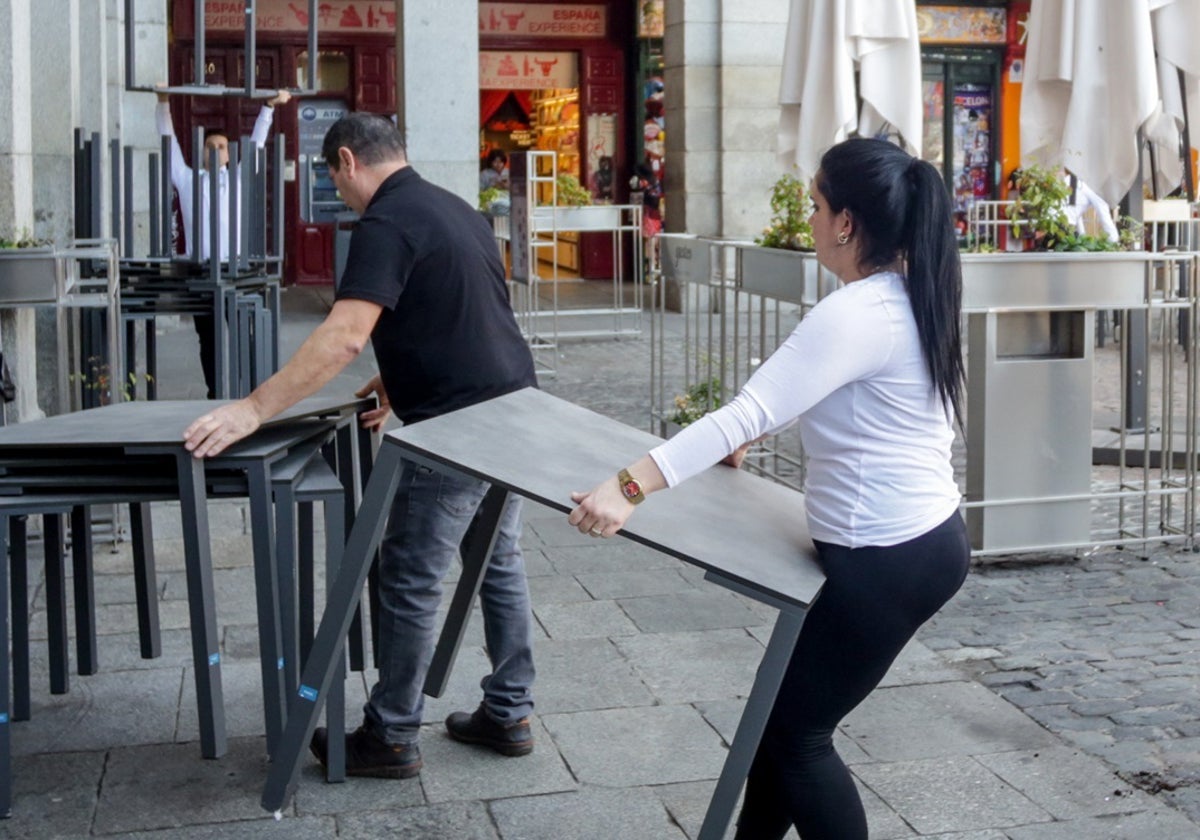 Varios empleados de un bar de la Plaza Mayor de Madrid recogen la terraza