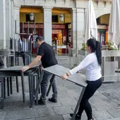 Varios empleados de un bar de la Plaza Mayor de Madrid recogen la terraza