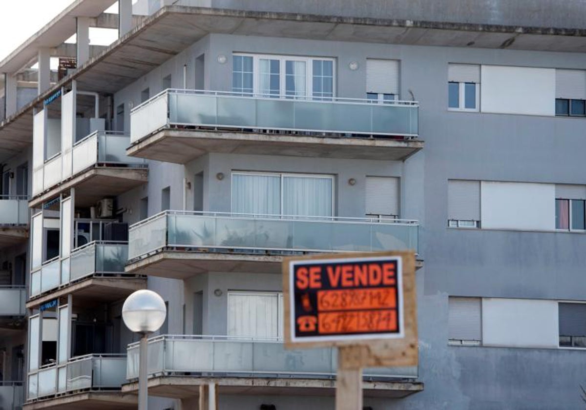 Un cartel de 'se vende' frente a un bloque de viviendas