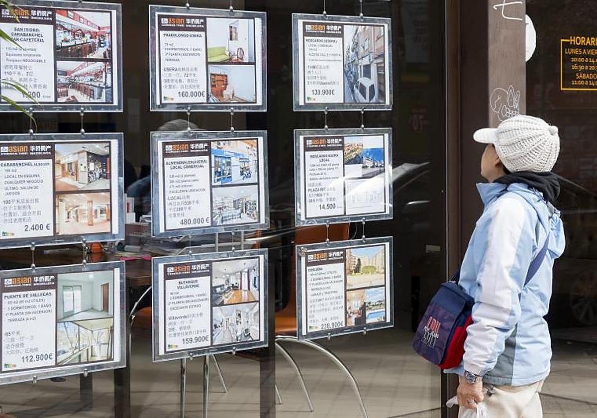 Imagen de archivo de una persona extranjera mirando el escaparate de una inmobiliaria