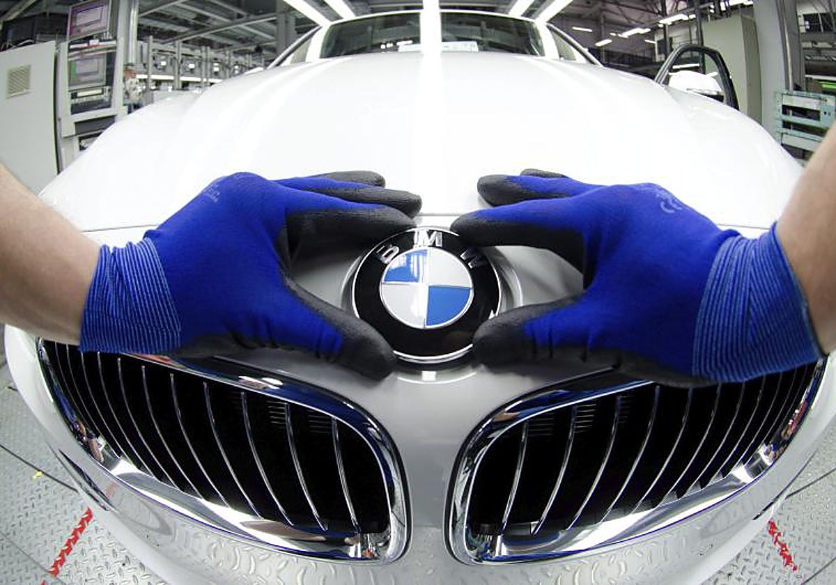 Un empleado coloca un logotipo de BMW en un coche