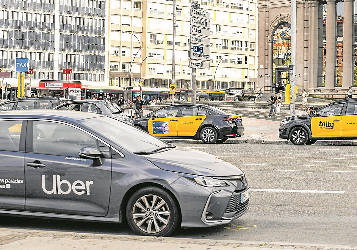 Un VTC y dos taxis estacionados en una avenida de Barcelona