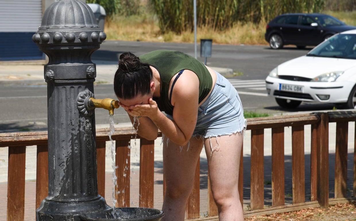 Una joven se refresca en una fuente para sobrellevar las altas temperaturas