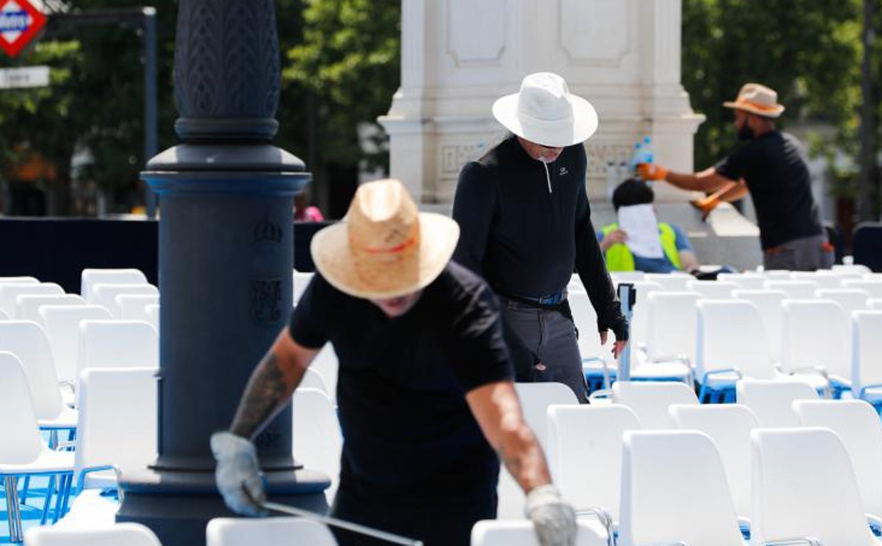 Varios trabajadores visten sombreros para protegerse de la ola de calor en Madrid