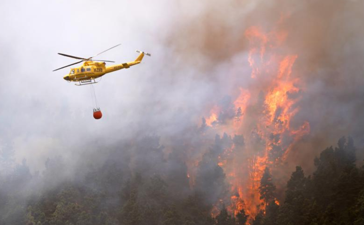Un helicóptero contra incendios descarga agua sobre un incendio forestal en Tenerife Norte