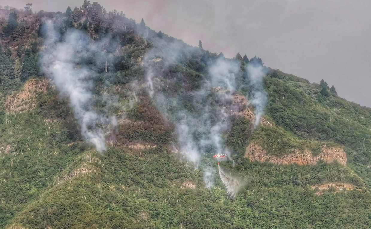 Un helicóptero trata de apagar los puntos calientes que siguen humeantes de las laderas