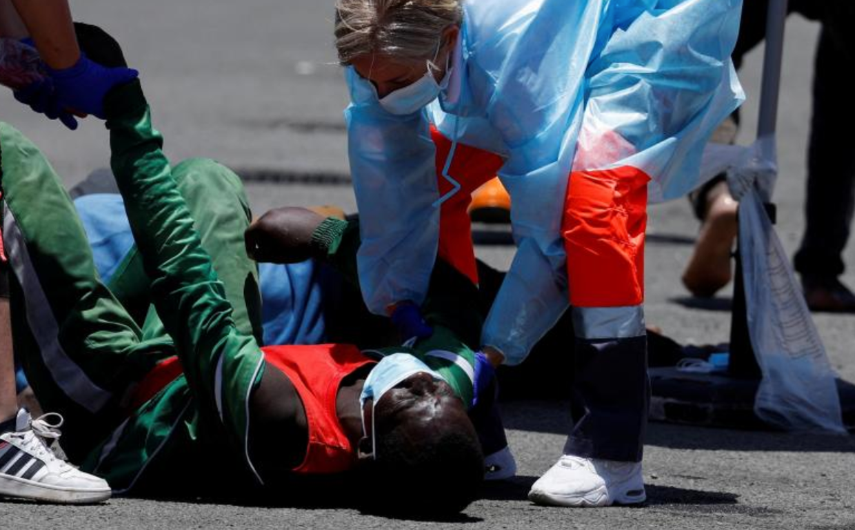 Un migrante es ayudado por los equipos de asistencia humanitaria en su llegada al muelle