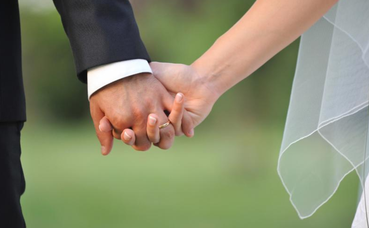 Una pareja se da la mano en su boda en foto de archivo