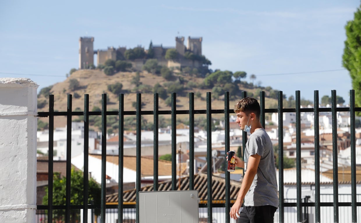 Un joven pasea por una calle de Almodóvar del Río con su castillo al fondo
