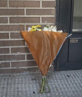 Imagen secundaria 2 - Exterior del edificio en el que tuvo lugar el asesinato machista, con un ramo de flores que recuerda a las víctimas y la puerta del domicilio todavía precintada