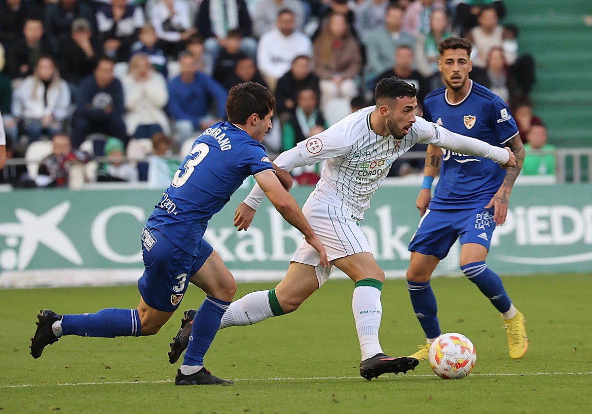 Carlos Puga conduce el balón ante dos rivales