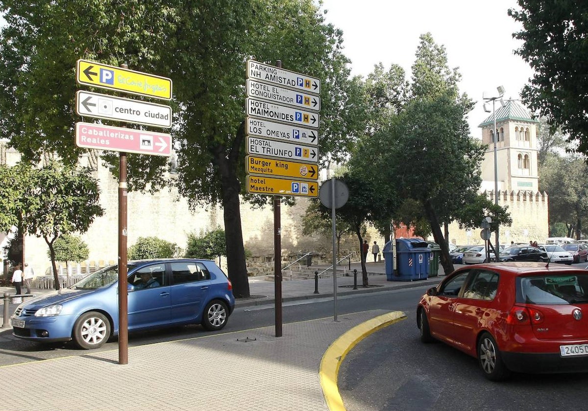 Dos coches circulan por la Puerta de la Media Luna de Córdoba, en pleno Casco