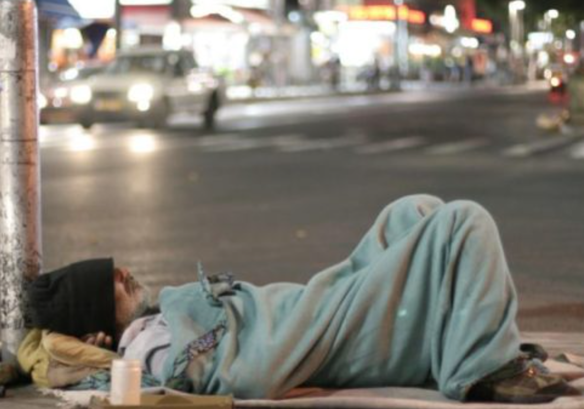 Un hombre en situación de sinhogarismo pernocta en la calle en foto de archivo