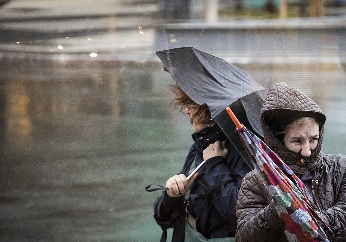 Dos mujeres avanzan con dificultad y el fuerte viento en las calles de San Sebastián