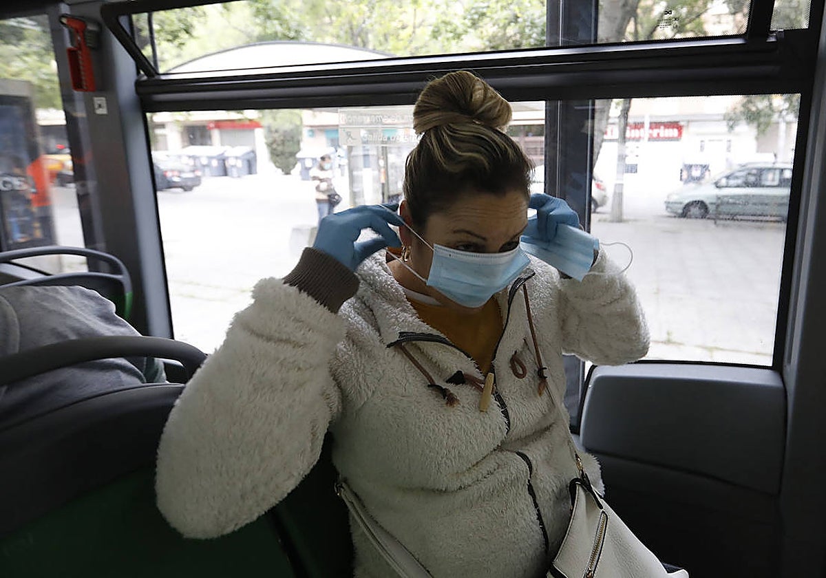 Una mujer se pone la mascarilla en un autobús de Córdoba