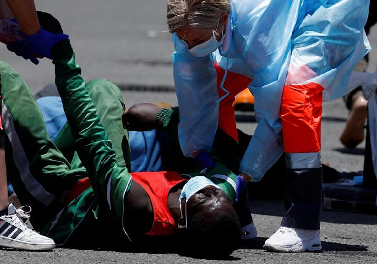 Sanitarios atienden a un migrante en su llegada al muelle de Arguineguín