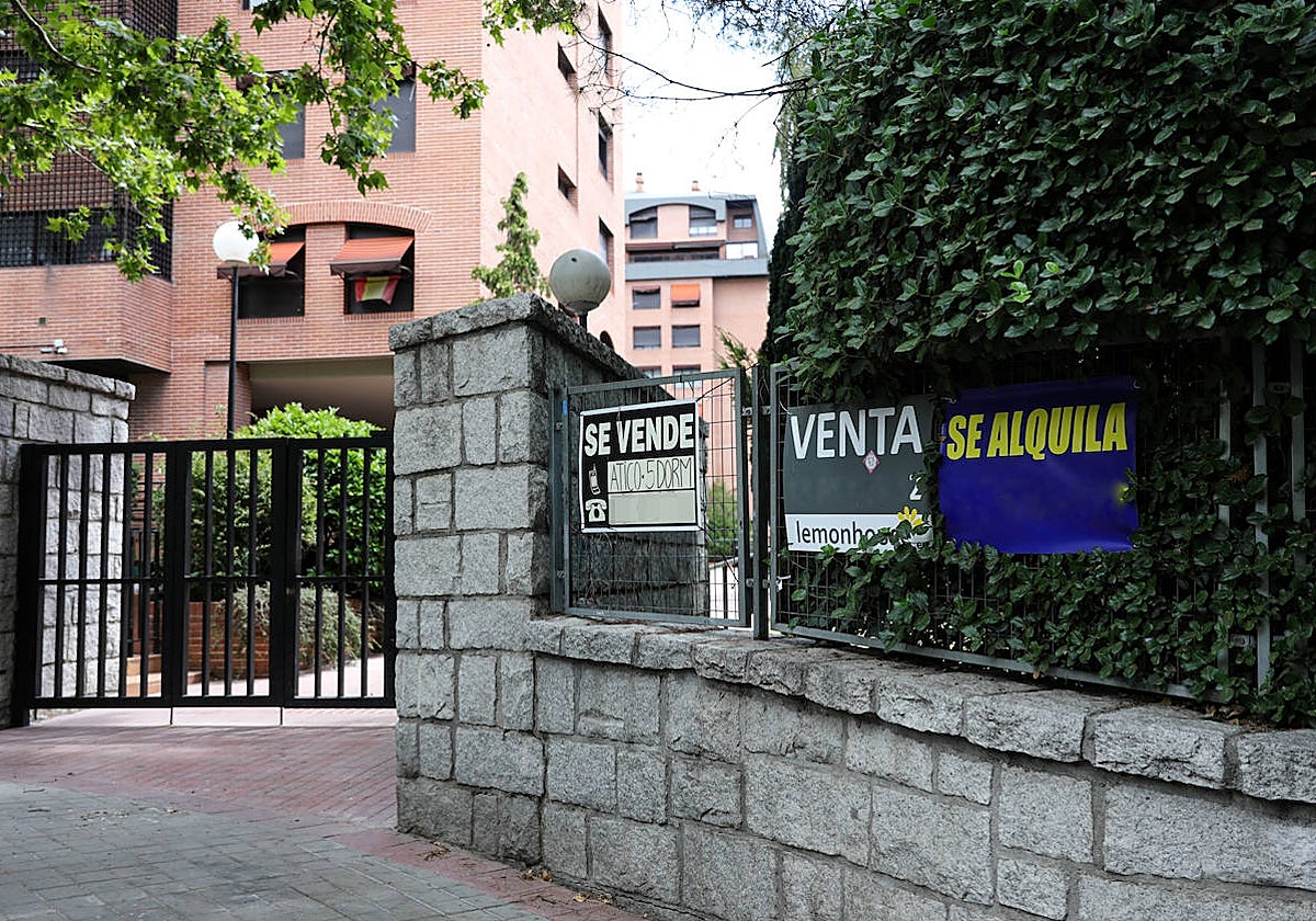 Carteles de venta y alquiler de pisos a las puertas de una urbanización en Madrid