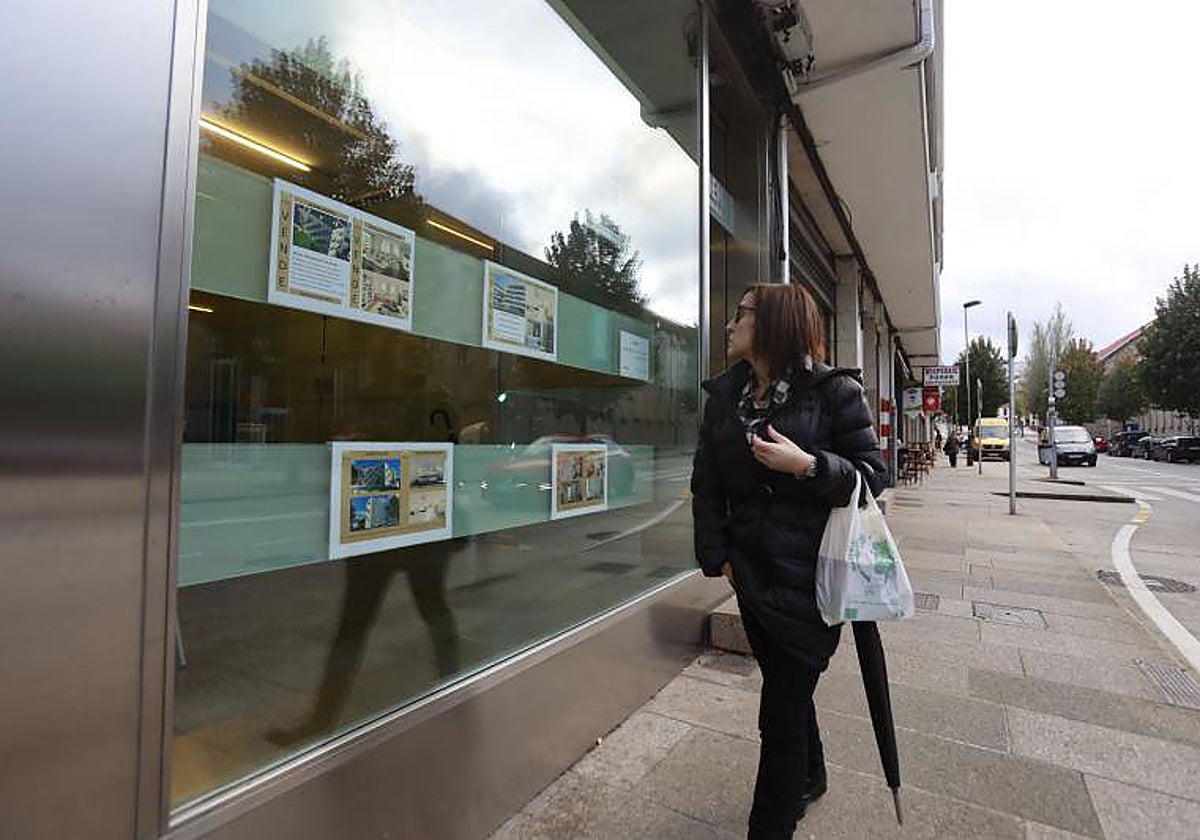 Una mujer mira el escaparate de una inmobiliaria en Santiago, en una imagen de archivo