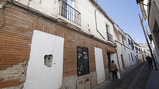 Dos vecinos junto a una casa abandonada en el barrio
