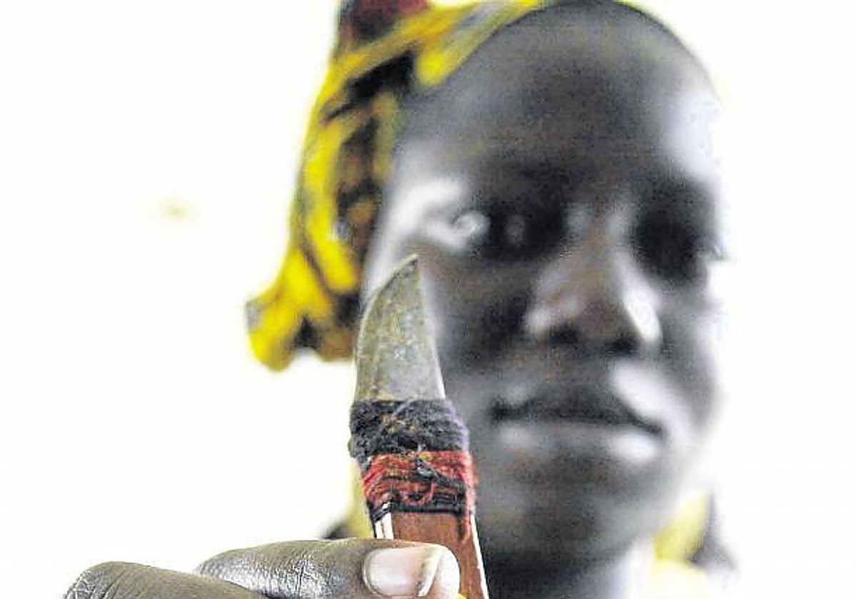 Una niña muestra un estilete utilizado para la mutilación femenina en Costa de Marfil