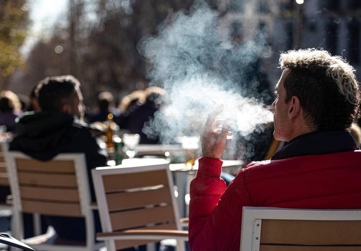 Un hombre fuma en una terraza