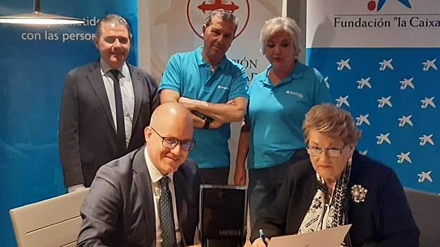 Amador Carmona y Olga Caballero firman el convenio, ante Manuel  Murillo y dos de los voluntarios