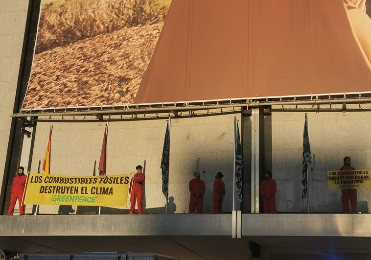 Activistas de Greenpeace despliegan pancartas en un tejadillo de El Corte Inglés de Nuevos Ministerios