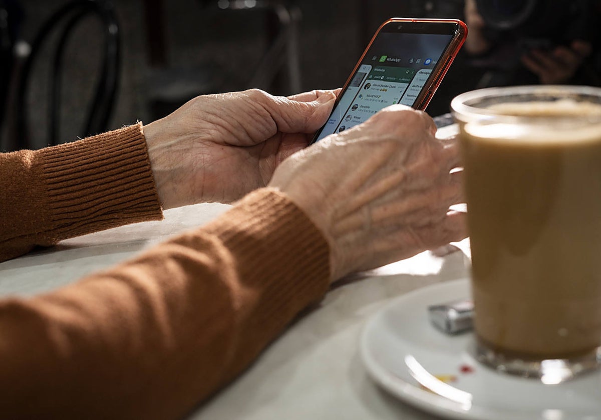Una mujer mayor utiliza la aplicación de WhatsApp en su móvil