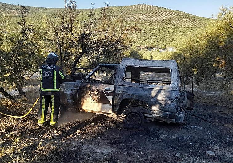 Bomberos sofocando las llamas de un todoterreno incendiado que había sido robado