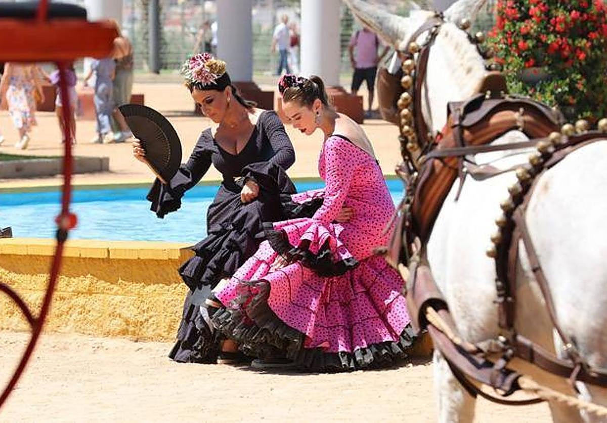 Dos mujeres vestifas de flamenca, junto a la portada de la Feria de Córdoba el año pasado