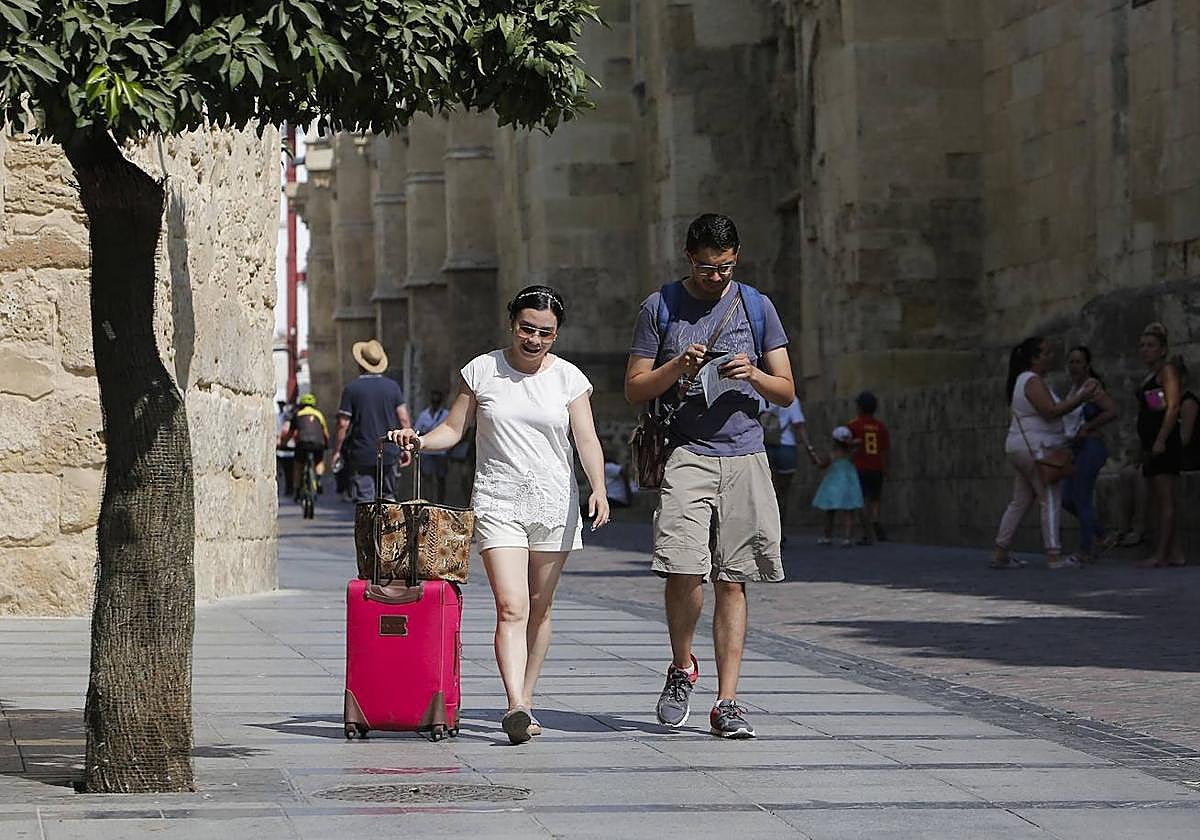 Una pareja de turistas con su maleta, en el entorno de la Mezquita-Catedral