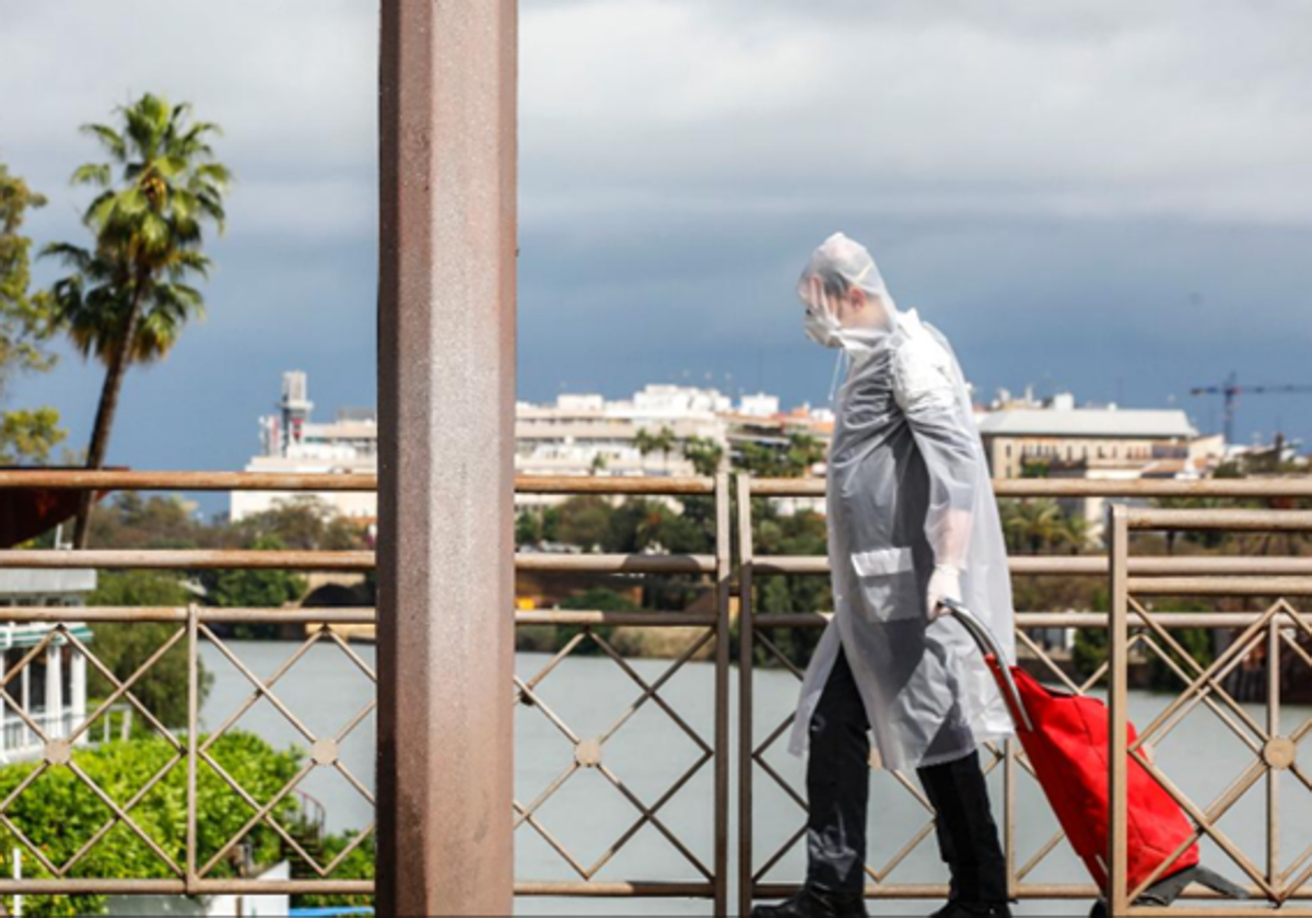 Un hombre camina por el Puente de San Telmo de Sevilla un día de tormenta