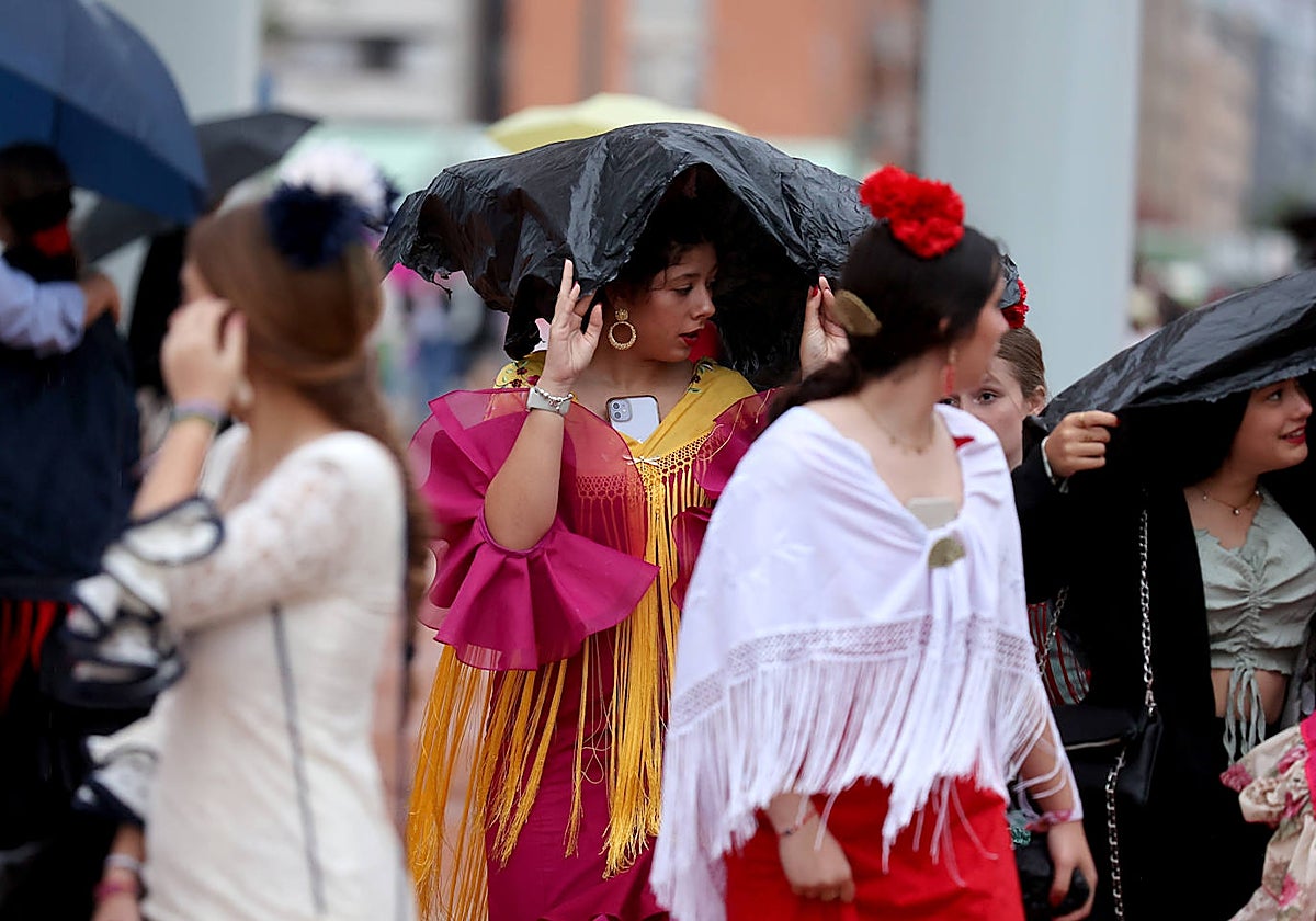 Varias jóvenes se protegen de la lluvia en la Feria de Córdoba