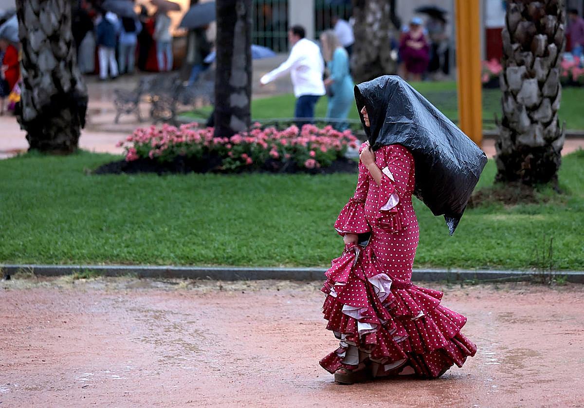 Una mujer vestida de flamenca bajo la lluvia el pasado sábado en la Feria de Córdoba
