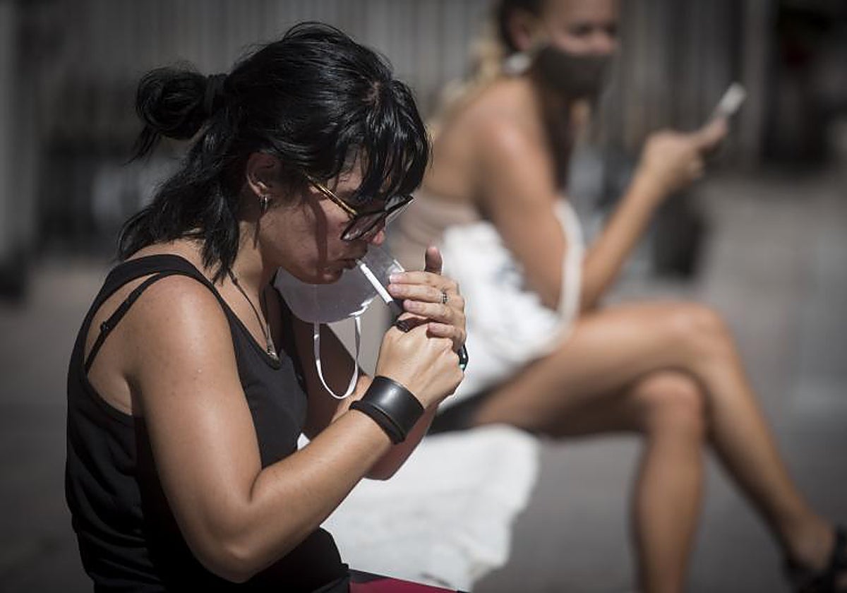 Una mujer enciende un cigarro en una calle de Madrid