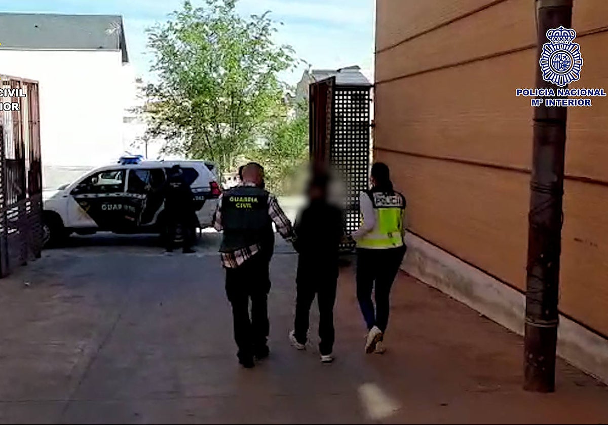 Uno de los detenidos es conducido por agentes de la Policía Nacional y Guardia Civil