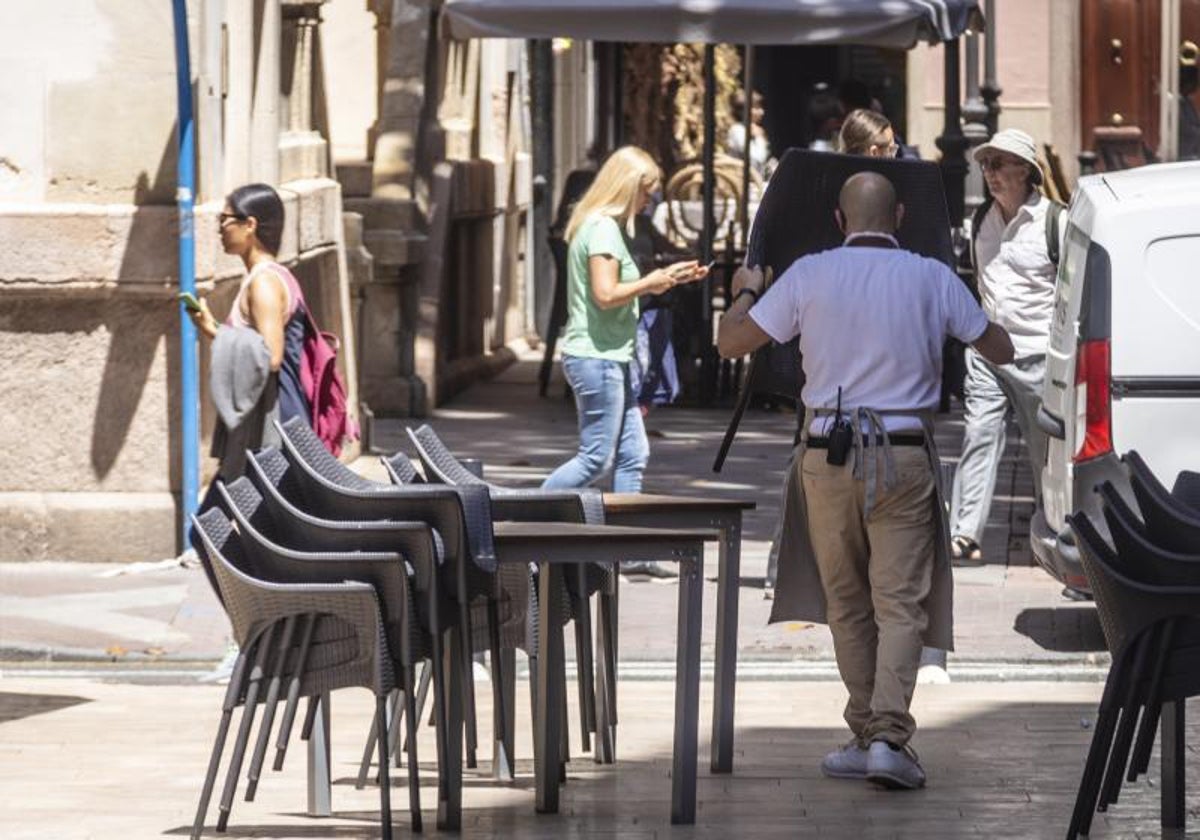 Imagen de archivo de un camarero montando la terraza de un restaurante