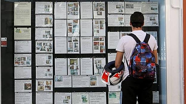 Un joven observa la oferta de pisos de una inmobiliaria en la capital