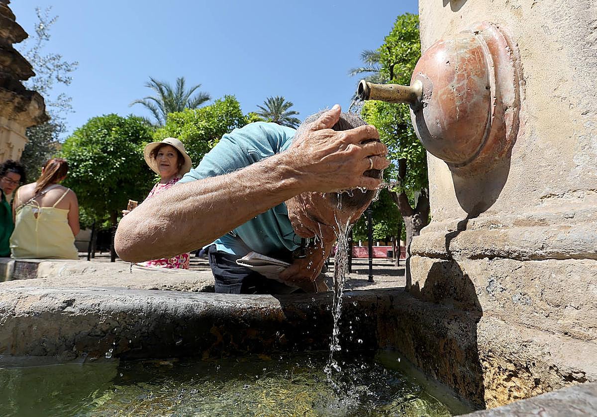 Un hombre se refresca bajo una de las fuentes del Patio de los Naranjos