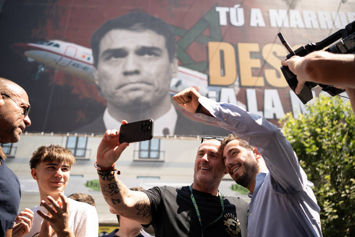 Dos personas fotografiándose con el fondo de la lona de Desokupa