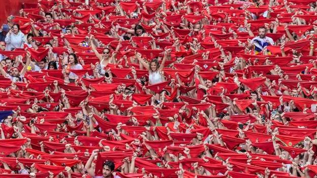 Los pamploneses levantan sus pañuelos rojos momentos antes del chupinazo que abre los Sanfermines.