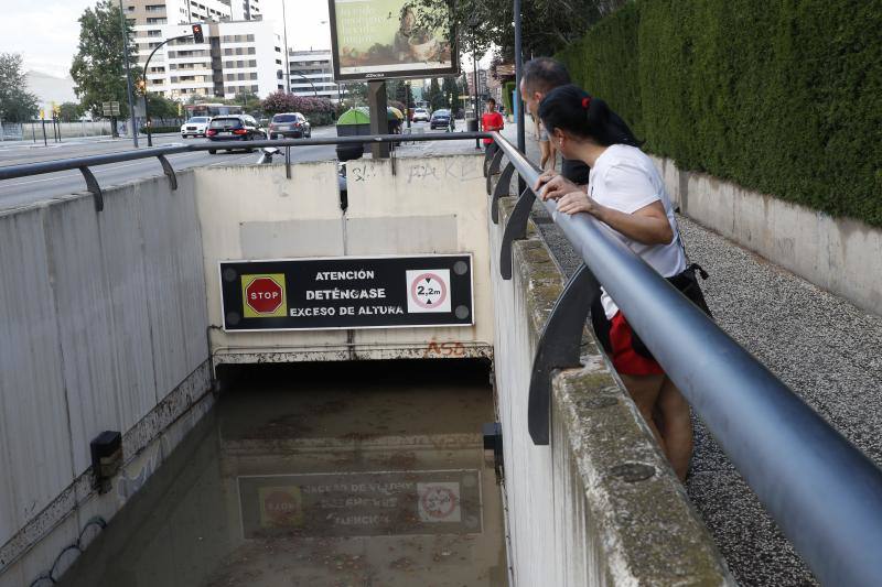 Dos personas observan el nivel alcanzado por el agua, de casi dos metros de altura, en un paso subterráneo este jueves en Zaragoza.