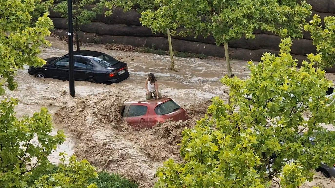 Una mujer sobre el techo de un vehículo durante la tromba de agua