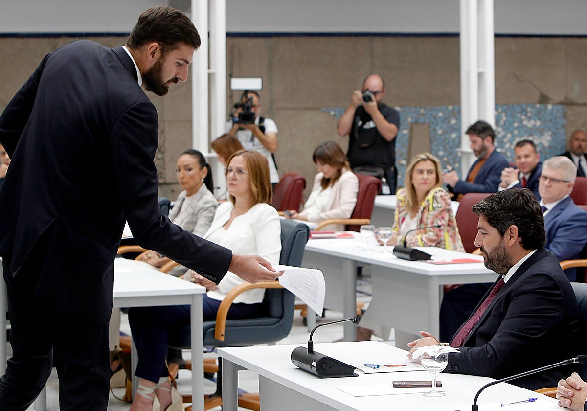 Antelo, portavoz de Vox, entrega al popular López Miras una propuesta de acuerdo durante el debate de este lunes